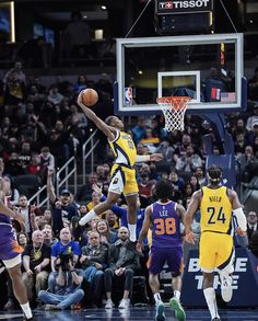 the basketball player is going to dunk the ball in front of the other players