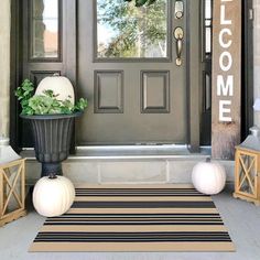 the front door is decorated for fall with white pumpkins and greenery in pots