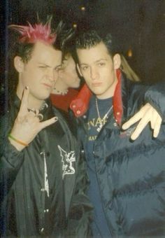 two young men standing next to each other in front of a building with punk hair