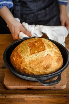 a loaf of bread sitting in a skillet on top of a wooden table