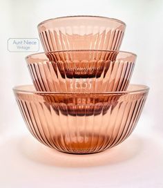 three pink glass bowls stacked on top of each other in front of a white background