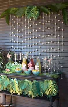 a table topped with lots of bottles and glasses filled with drinks next to palm leaves