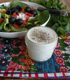 a bowl of salad with dressing next to it