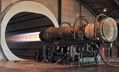 a large metal object sitting inside of a building next to a hose and some wires