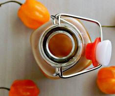 a jar filled with liquid sitting on top of a table next to oranges and peppers