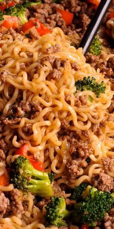 a close up of noodles and broccoli with chopsticks