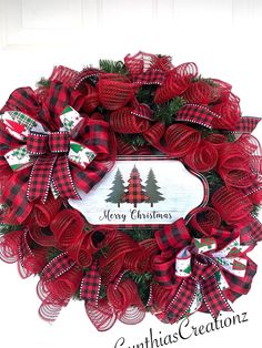 a christmas wreath with red and black plaid bows on it, hanging from the front door