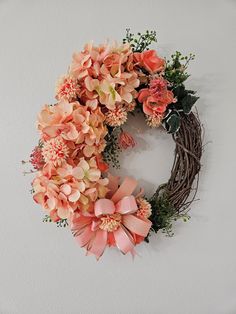 a wreath with pink flowers and greenery hanging on the wall