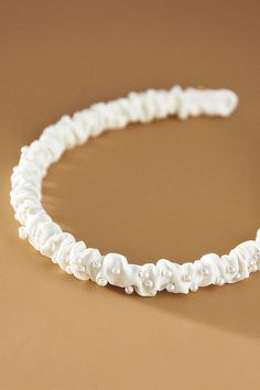 a white headband with pearls and beads on it's side, sitting on a brown surface