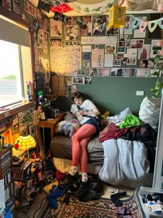 a woman sitting on top of a bed in a room with lots of clutter