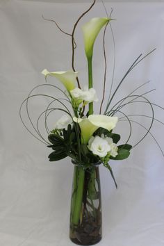 a vase filled with white flowers and greenery