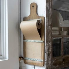 a roll of toilet paper is hanging on the wall next to a wooden cutting board