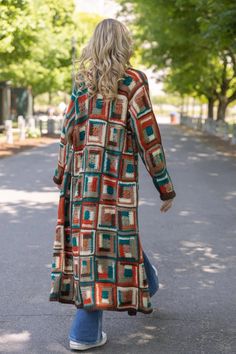 a woman is walking down the street wearing a colorful coat