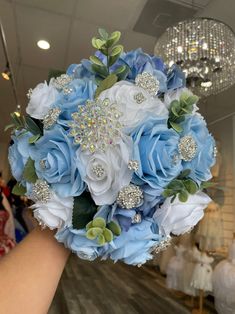 a bridal bouquet with blue and white flowers is held by a woman's hand