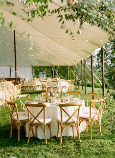 an outdoor tent with tables and chairs set up for a wedding reception under the canopy