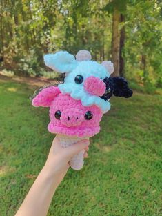 a hand holding up a crocheted toy with two small stuffed animals on it