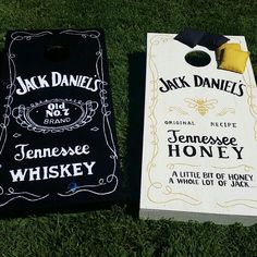 two cornhole game boards laying on the grass with jack daniels and tennessee honey written on them