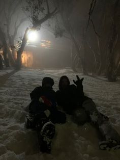 two people sitting in the snow at night