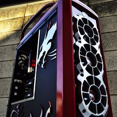 a red and black computer case sitting on top of a brick wall next to a building