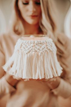 a woman holding a white lamp with fringes on it's lampshade