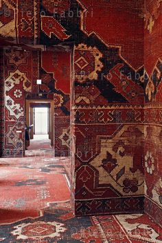 an ornately decorated room with red and black rugs on the floor, in front of a doorway