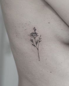 a woman's stomach with a single flower tattoo on her left side ribcage