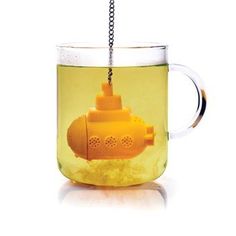 a yellow fire hydrant in a tea cup with chains hanging from it's handle