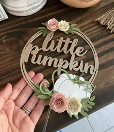 a hand holding a paper cutout with the words little pumpkin and flowers on it