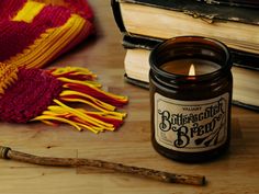 a candle sitting on top of a wooden table next to books and a knitted hat