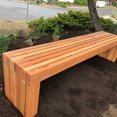 a wooden bench sitting in the dirt near a tree