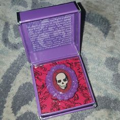 a purple and red box with a skull on the inside is sitting on a carpet