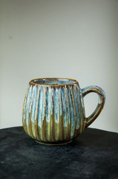 a ceramic cup sitting on top of a black table next to a white and gray wall