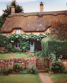 a thatched roof house with flowers growing around it