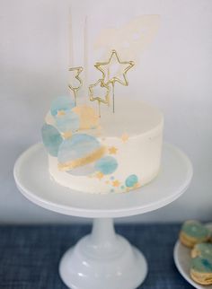 a white cake sitting on top of a table next to cookies