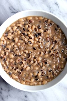 a white bowl filled with beans on top of a marble counter next to a spoon