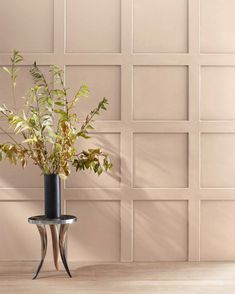 a plant in a vase sitting on a table next to a wall with some tiles