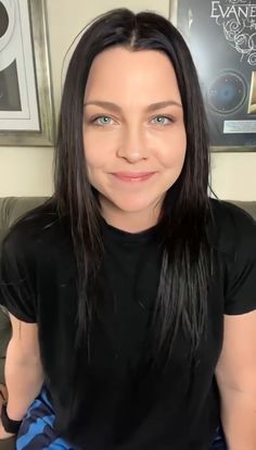 a woman with long black hair is looking at the camera