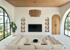 a large living room with white furniture and arched doorways leading to an outside patio