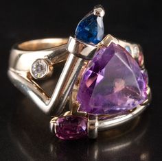 14k Yellow Gold Amethyst Sapphire Ruby Aquamarine Diamond Abstract Ring 5.45ctwMetal Information: 14k Yellow GoldTotal Weight: 13.48gBand Width: 3.4mmSize: 6.25Stone InformationMain StoneGem Type: AmethystShape: Trillion (12mm x 12mm)Color: PurpleClarity/Quality: BCarat Weight: 4.10ctNumber of Stones: 1Accent StonesGem Type: SapphireShape: Pear (5mm x 4mm)Color: BlueClarity/Quality: ACarat Weight: .45ctNumber of Stones: 1Accent StonesGem Type: RubyShape: Oval (6mm x 4mm)Color: RedClarity/Quality Aquamarine, Ruby, Sapphire, Amethyst, Yellow Gold, Yellow, Stone, Gold, Color