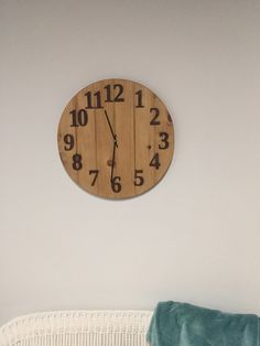 a wooden clock mounted to the side of a wall next to a green throw pillow