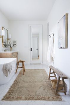 a white bathroom with a rug, sink and bathtub in it's center