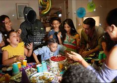 a group of people sitting around a table with cake and confetti in front of them