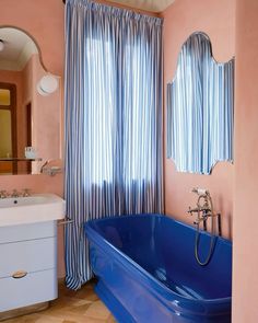 a blue bath tub sitting under a bathroom mirror