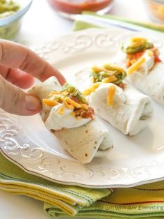 a person is taking a burrito out of the wrapper on a white plate