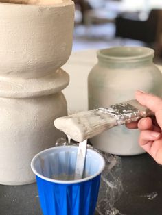 a person is pouring something into a blue cup