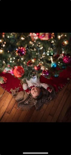 a baby is laying on the floor next to a christmas tree