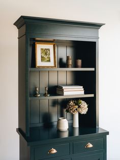 a black bookcase with flowers and books on it