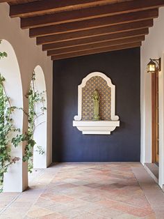 an archway with a clock on the wall next to plants and potted planters