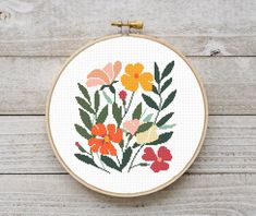 a cross stitch pattern with flowers in it on a wooden table next to scissors and thread