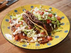 two tacos with lettuce and tomatoes on a yellow plate